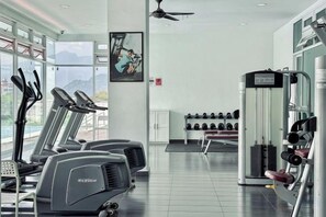 Une salle de sport équipée de tapis de course, d’appareils de musculation et d’haltères.