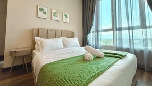 Ett hotellrum med en säng, ett runt sidobord och ett fönster med gardiner.
