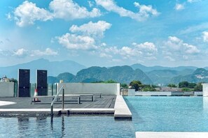 A rooftop infinity pool with a view of mountains, a wooden deck, and two black doors. - D'Festivo Residence Ipoh by PLY Home (Ipoh)
