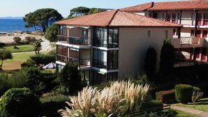 Een hotel met meerdere verdiepingen, balkons, uitzicht op het strand en een verzorgde tuin.