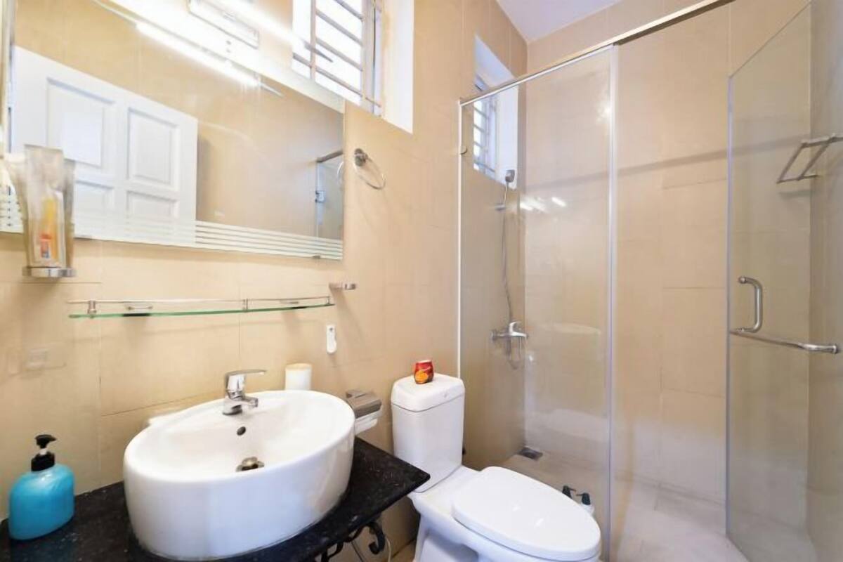 Un baño con lavamanos, inodoro y ducha con mampara de vidrio.