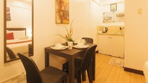 Une chambre d’hôtel compacte, équipée d’une table à manger pour deux personnes, d’un miroir, d’un tableau et d’une kitchenette.