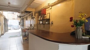 Un espace d’accueil comprenant un comptoir, un panneau d’information fixé au mur et un vase avec des fleurs.