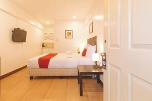 A hotel room with a bed, a bedside table, a lamp, a wall-mounted TV, and a door with a handle. - RedDoorz @ City Stay Inns Marilao (Marilao)