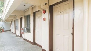 Un couloir avec des portes portant les numéros H-112, H-114 et H-116, qui donnent accès à des pièces individuelles.