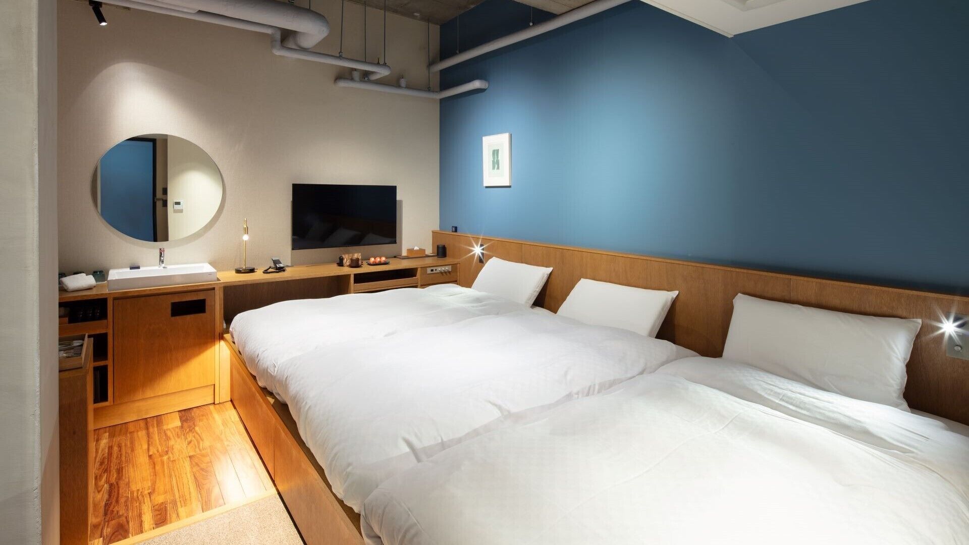 A hotel room with a large bed, a bedside table, a TV, a mirror, and a wooden cabinet.
