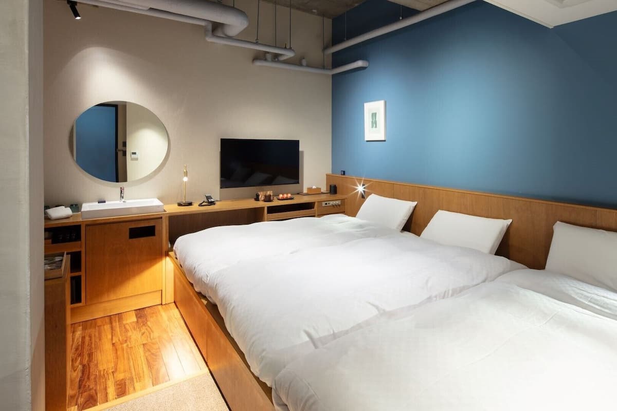 Une chambre d’hôtel avec un grand lit, une table de chevet, une télévision, un miroir et une armoire en bois.