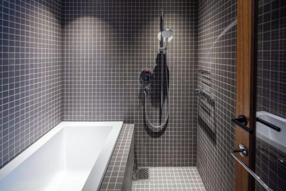 A modern bathroom with a bathtub, a shower, and a tiled wall.