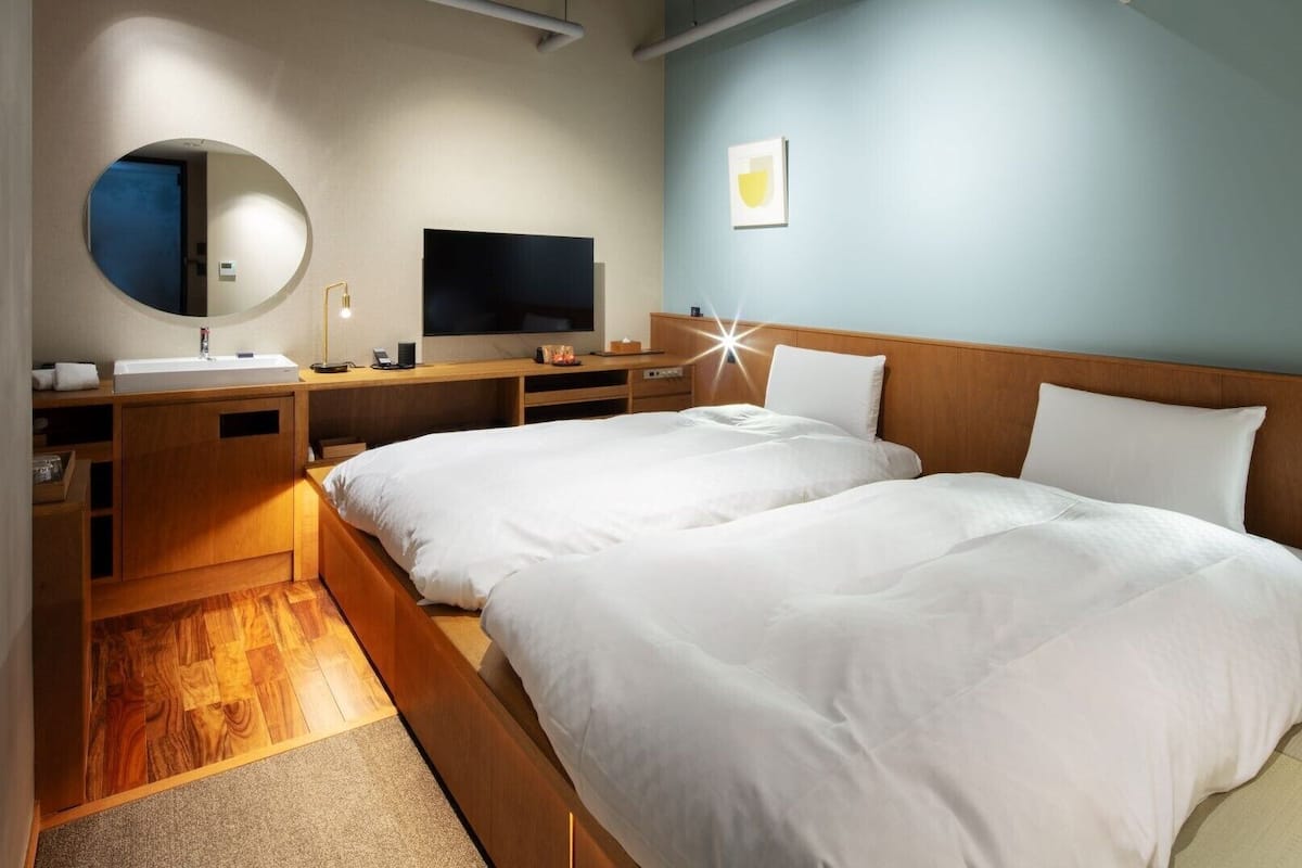 Une chambre d’hôtel avec un lit en bois, une télévision, un miroir et un bureau.