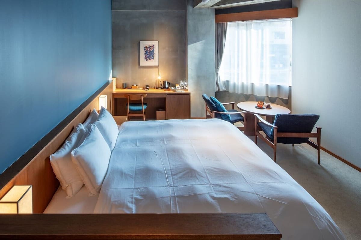 Une chambre d’hôtel avec un lit, un bureau, une chaise et une petite table.