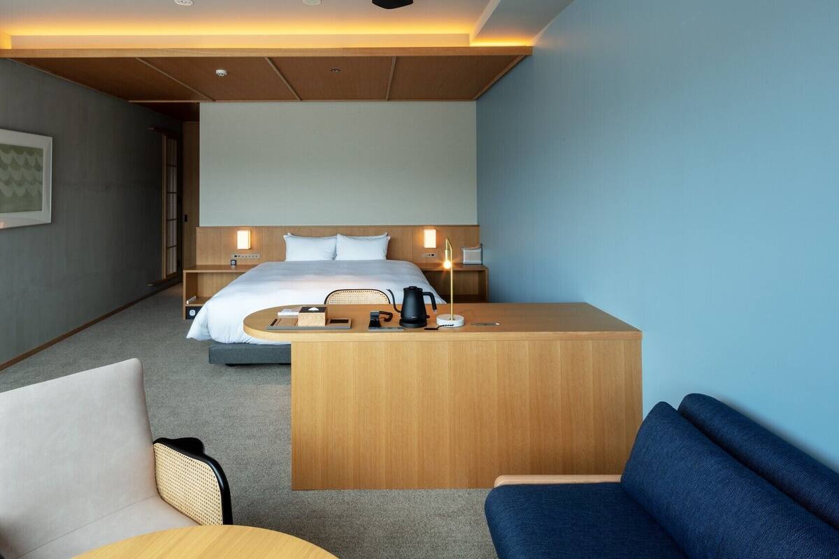 Une chambre d’hôtel comprenant un lit, des tables de chevet, un bureau, une chaise et un canapé.
