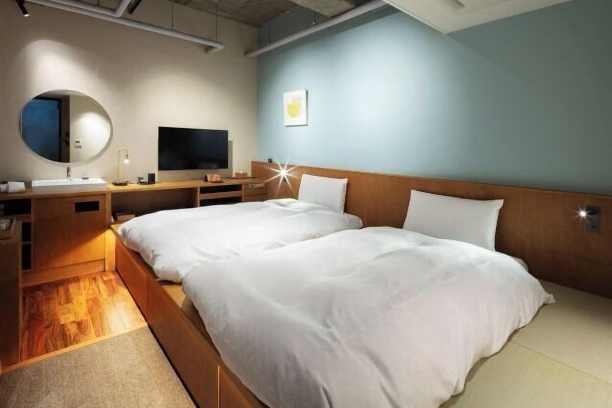 Une chambre d’hôtel avec un lit, une télévision, un miroir et un bureau avec une lampe.