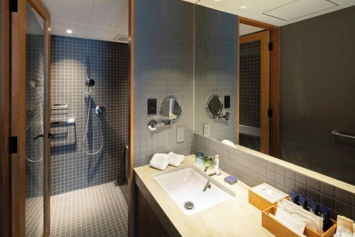 A modern bathroom with a shower, a sink, and a large mirror.