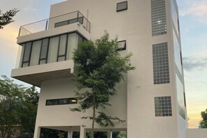 Un bâtiment moderne à la façade plate, doté de grandes fenêtres et d’un balcon.