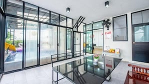 Una cocina moderna con una mesa de comedor de vidrio, puertas correderas con marco negro y vistas a una piscina exterior.