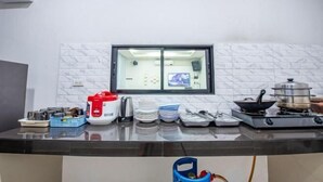 Una cocina con ventana, estufa y diversos utensilios y electrodomésticos.