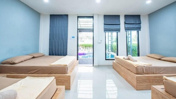 Una habitación moderna con dos camas, un ventanal grande y vista a una piscina.