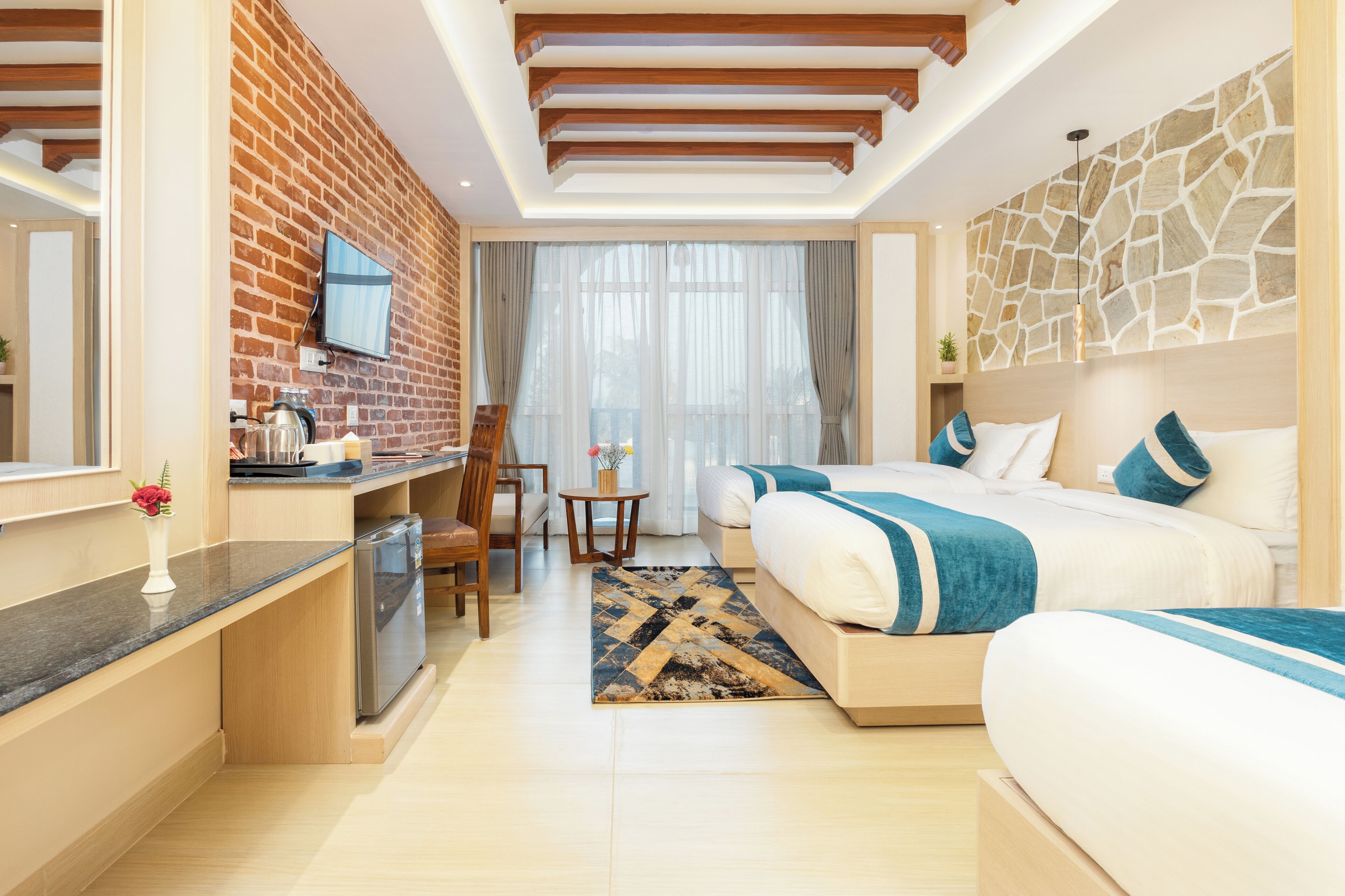 Ein modernes Hotelzimmer mit Küchenzeile, einem Esstisch und einem großen Bett mit blauer Bettwäsche.