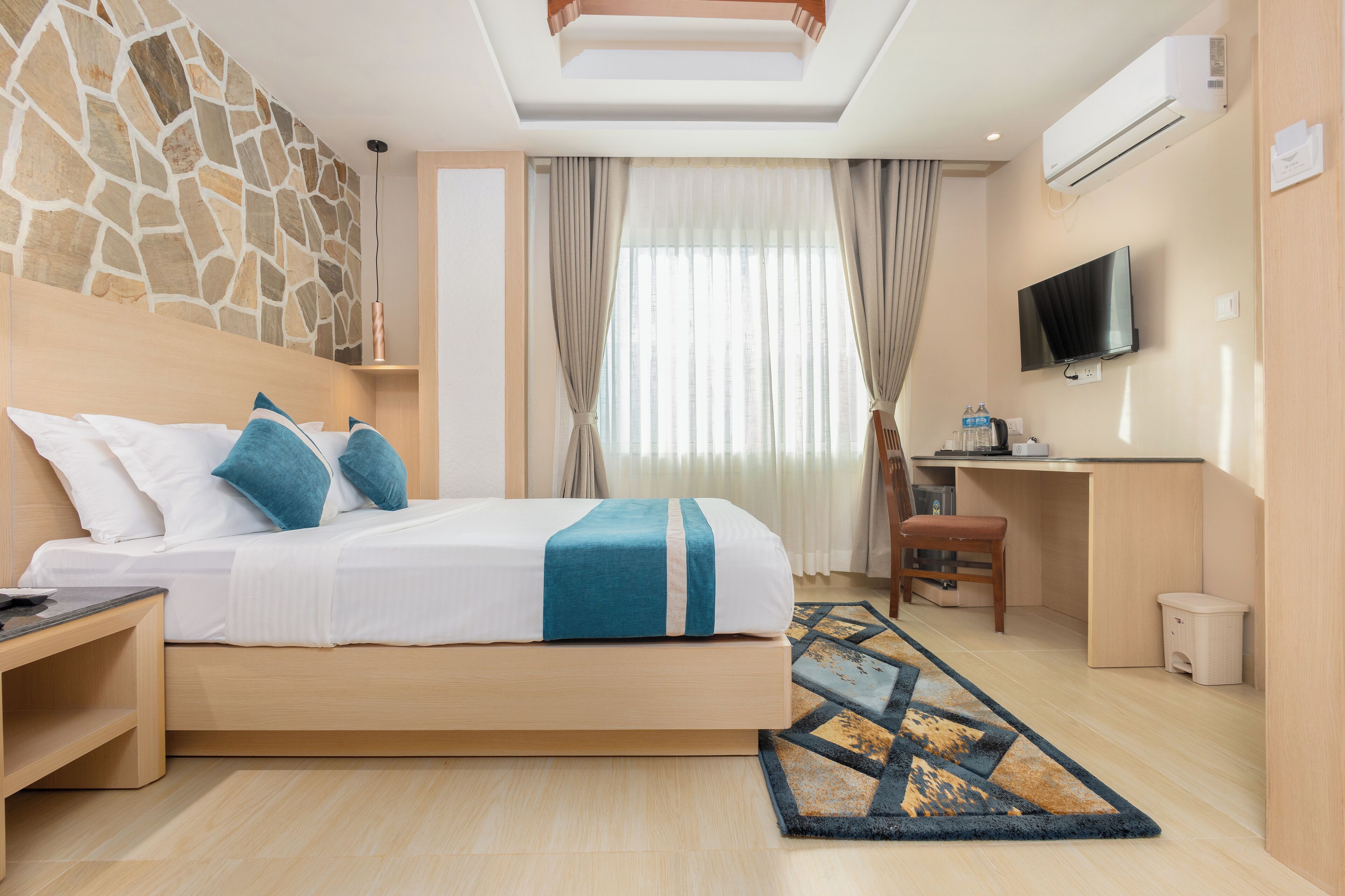 Ein Hotelzimmer mit Bett, Schreibtisch, Fernseher und einer Steinwand.