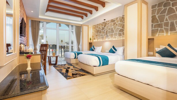 A modern hotel room with a large bed, a smaller bed, a desk, and a balcony with a view. - Tulsi Kathmandu Hotel (Kathmandu)