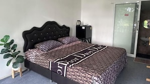 A bedroom with a bed, a small plant, a heater, and a sliding door to a bathroom. - INK-PHA GARDENVIEW RESORT (Noen Maprang)