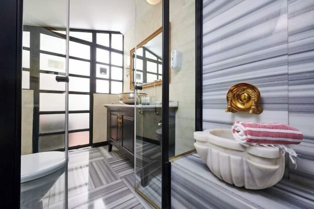 A modern bathroom with a glass shower enclosure, a toilet, a sink, and a decorative towel rack.