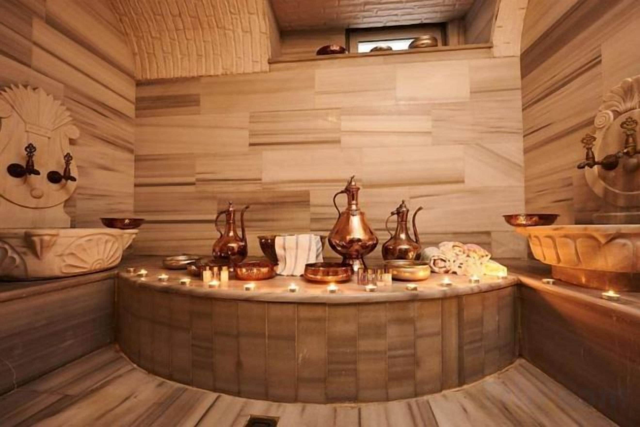 A spa area with a circular seating arrangement, copper vessels, and candles.