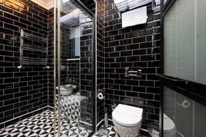 Une salle de bain avec des carreaux noirs et blancs formant un motif, une douche en verre et des toilettes blanches.