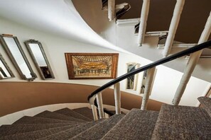 A spiral staircase with a handrail, a framed picture on the wall, and a window to the right. - FAIK PASHA HOTELS (Istanbul)