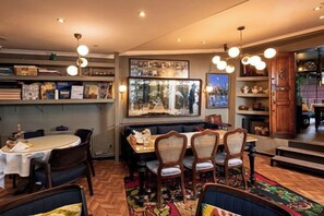 Un espace repas comprenant une table ronde, des chaises, un banc et un tapis à motifs.