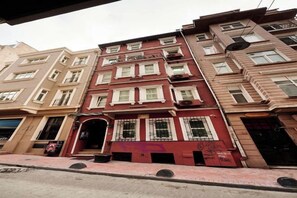 Un immeuble à plusieurs étages, doté d’une façade rouge et de fenêtres blanches.