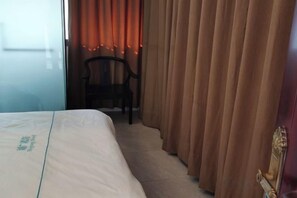 A hotel room with a bed, curtains, a chair, and a window. - Vientiane Huguang Hotel (Vientiane)