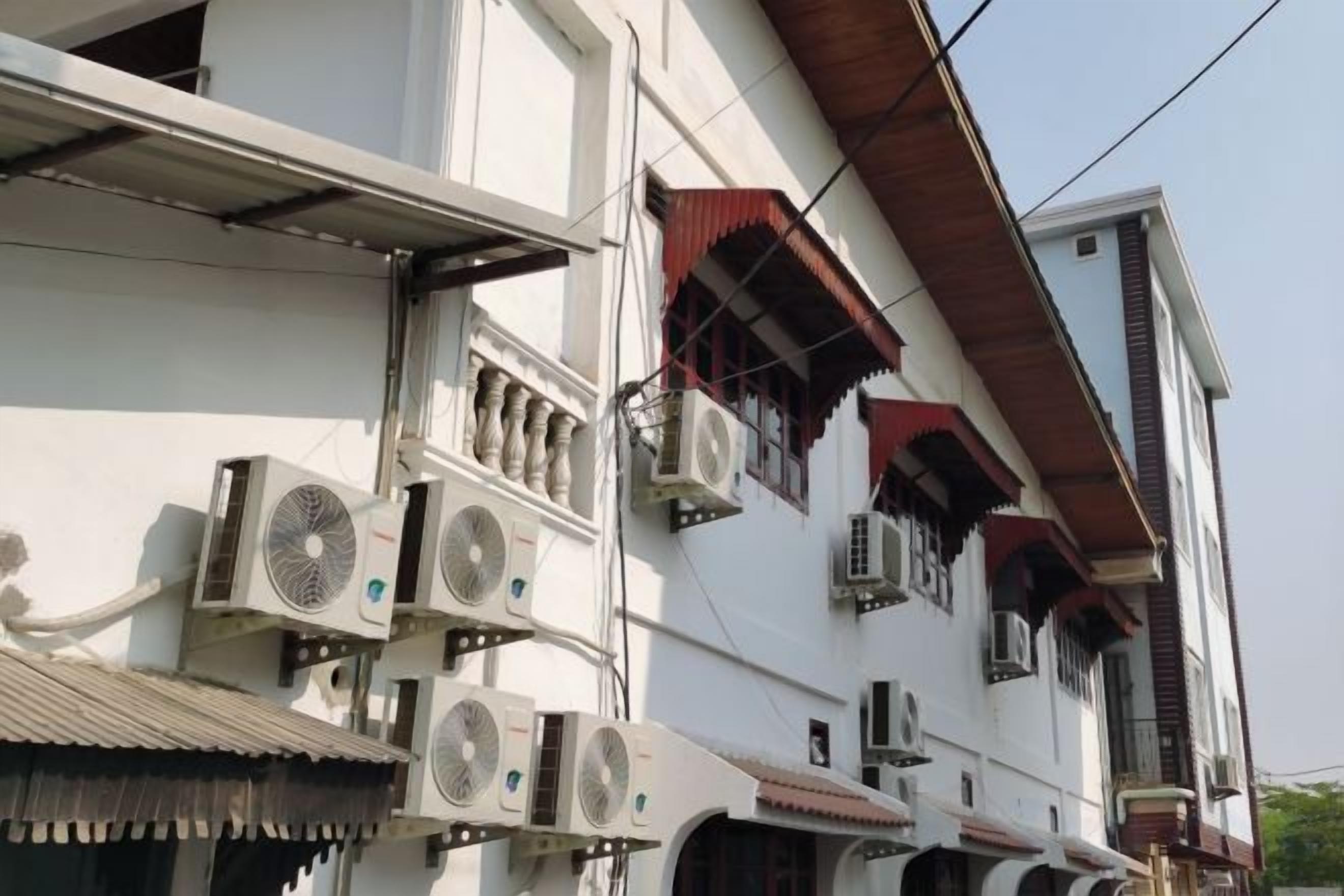 A multi-story building with multiple air conditioning units installed on the exterior.