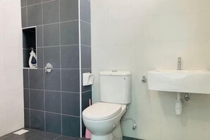 A bathroom with a toilet, sink, and shower area.