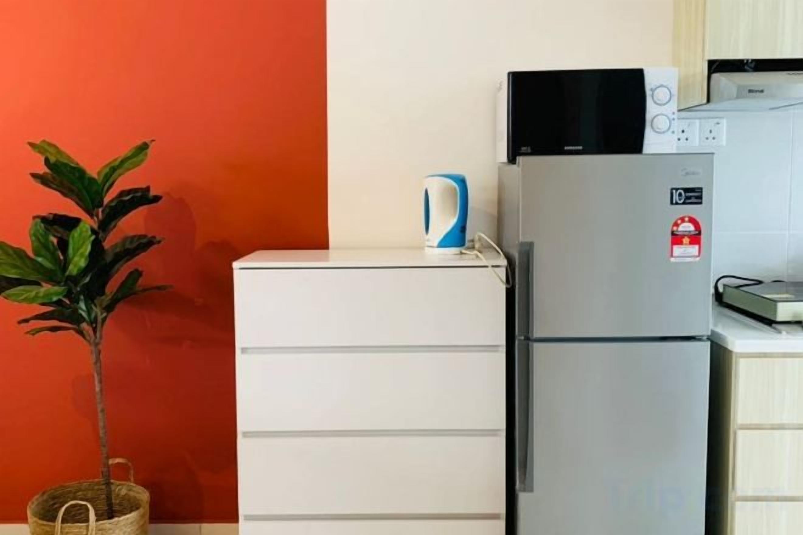 Una cocina con refrigerador, microondas y cafetera sobre la encimera.