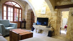 Un salon avec des murs en pierre, un téléviseur, un canapé et une table basse.