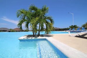 A swimming pool with a palm tree, lounge chairs, and a clear blue sky. - Relaxing Stay - Richmond Estate - 15mins Ocho Rios (St. Ann's Bay)