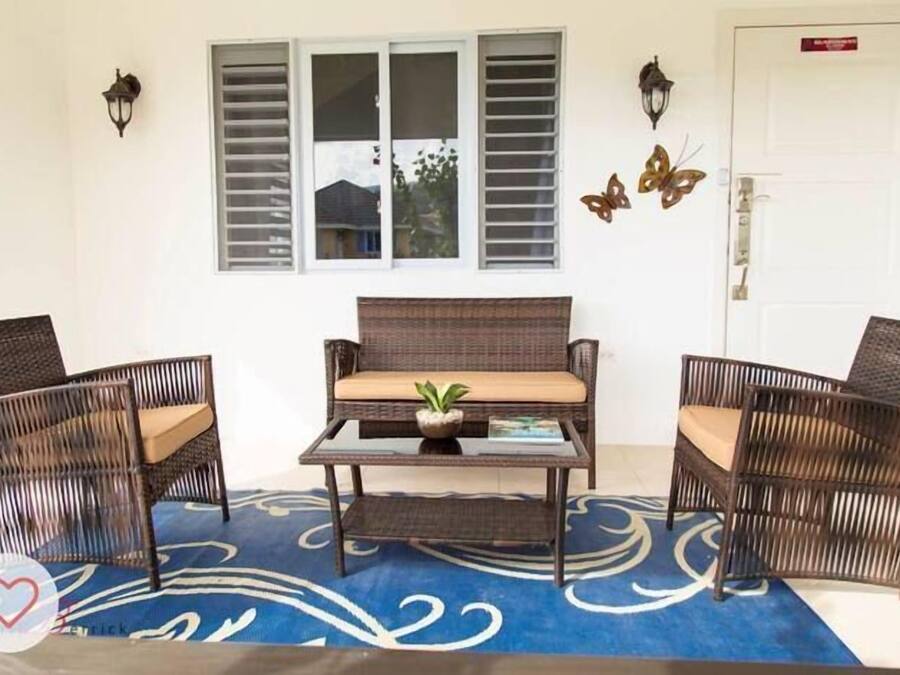 A room with a wicker sofa set, two chairs, a small table, and a potted plant.