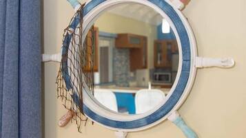 Un espejo circular montado en la pared con diseño de timón de barco, que incluye una cuerda y una pequeña figura colgando del timón.