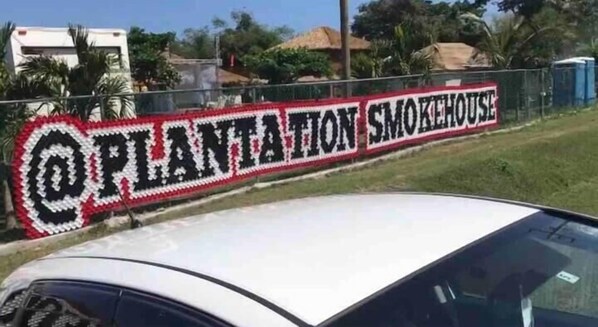 Una señal con el texto 'PLANTATION SMOKEHOUSE' en una fuente decorativa.