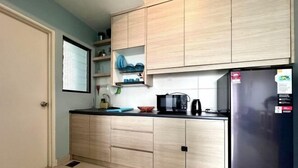A kitchen with light wood cabinets, a black refrigerator, and a window with blinds. - Sky River Front Kota Bharu @ AGhome (Kota Bharu)