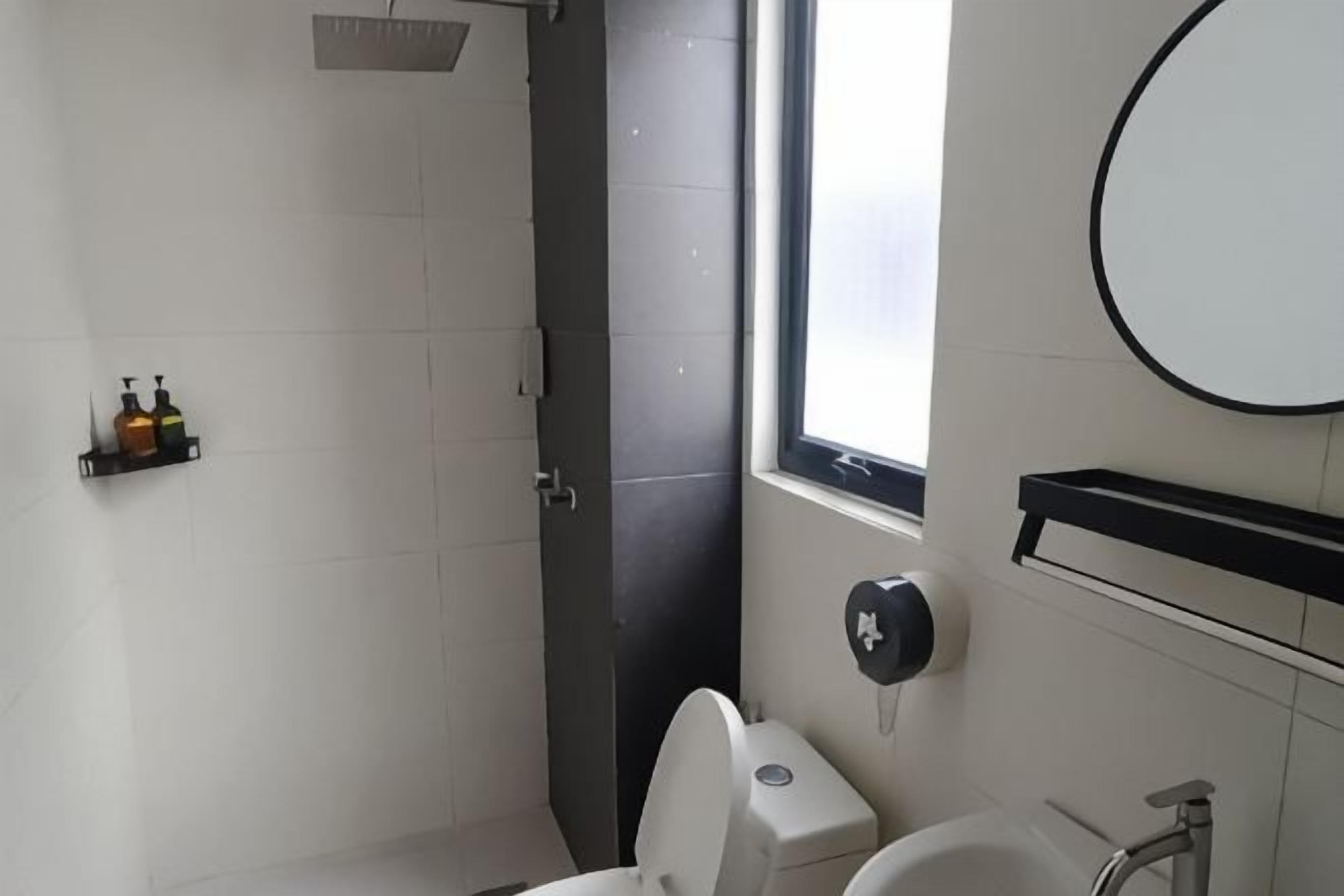 A bathroom with a toilet, sink, and a window.