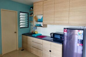 A kitchen with wooden cabinets, a stainless steel refrigerator, a microwave, and a sink. - Sky River Front Kota Bharu @ AGhome (Kota Bharu)