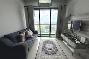 A modern living room with a sofa, TV, and a view through a large window. - Sky River Front Kota Bharu @ AGhome (Kota Bharu)