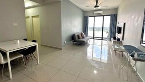 A spacious living area with a dining table, a sofa, a TV mounted on the wall, and a ceiling fan. - Sky River Front Kota Bharu @ AGhome (Kota Bharu)