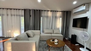 A modern living room with a sofa, a coffee table, and a TV. - Bangkok Cozy Garden Pool Villa Sukhumvit (Bangkok)