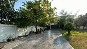 A paved pathway leading to a building with a white wall and a small tree. - Bangkok Cozy Garden Pool Villa Sukhumvit (Bangkok)