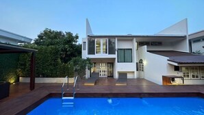 A modern house with a swimming pool, a covered patio, and a well-maintained garden. - Bangkok Cozy Garden Pool Villa Sukhumvit (Bangkok)