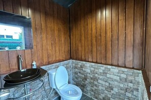 A bathroom with a wooden wall, a stone accent wall, a sink, and a toilet.