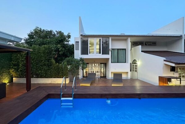 A modern house with a swimming pool, a covered patio, and a well-maintained garden.